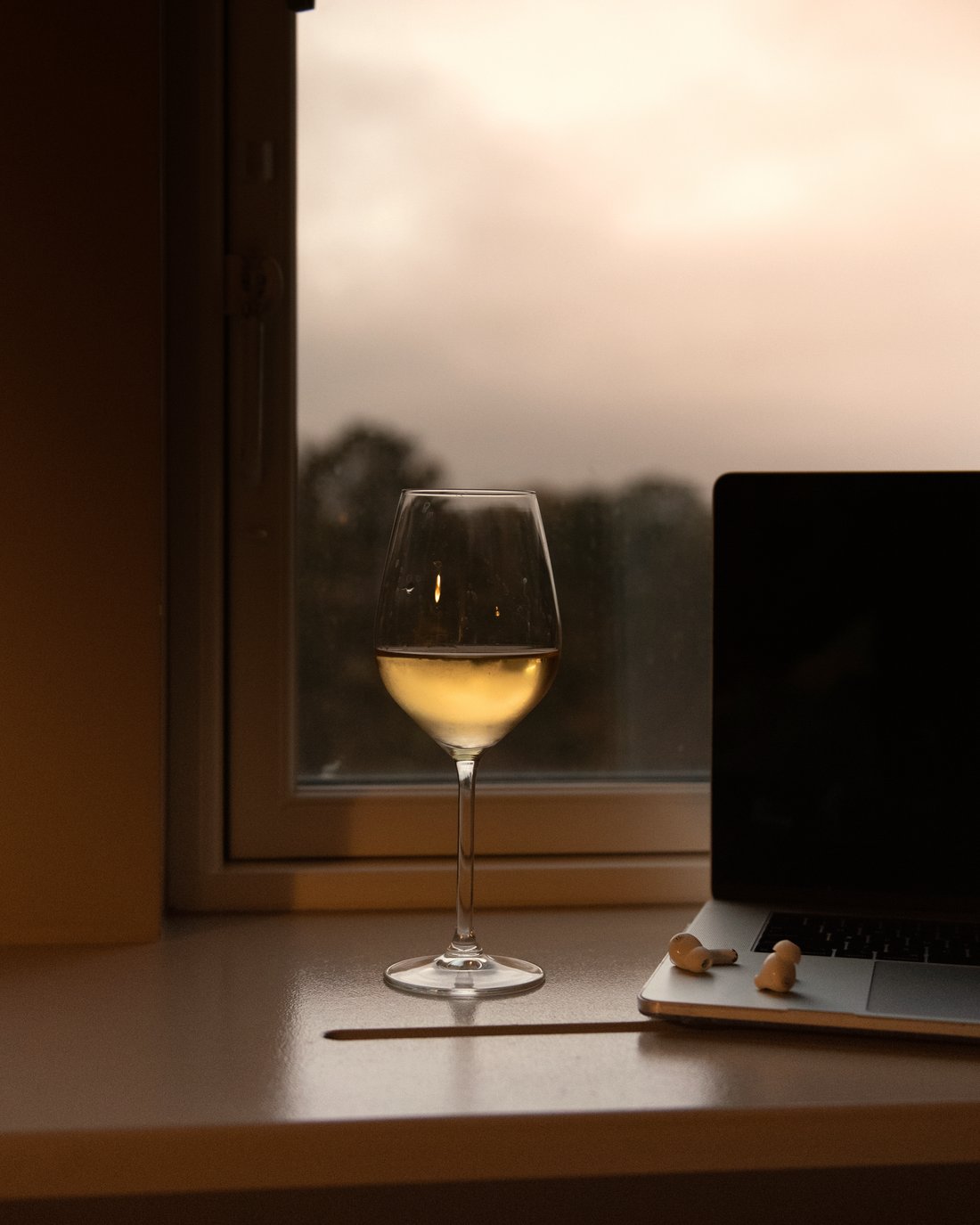 A glass of wine by a window at dusk